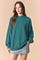 woman wearing a teal oversized sweatshirt and a light blue denim mini skirt