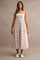woman wearing a floral print midi dress with a square neckline and a flowy skirt, paired with white sneakers