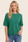 woman wearing a green short sleeve knit sweater with a relaxed fit and round neckline