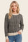 woman wearing a black and beige striped knit sweater with a relaxed fit and ribbed detailing
