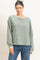 woman wearing a green striped long sleeve top with a white neckline, paired with blue jeans