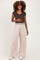 woman wearing a dark brown maternity short sleeve top and light beige wide-leg maternity pants