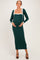 woman wearing a dark green maternity dress with a white bodice detail and a matching cardigan, showing her baby bump