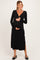 woman wearing a black long sleeve maternity dress with a v-neck and side slit, holding her baby bump