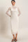 woman wearing a white ribbed midi dress with sheer long sleeves and a high neckline, styled with black strappy heels
