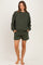 woman wearing a dark green maternity sweatshirt and matching shorts, pockets visible, comfortable casual style