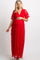 woman wearing a red lace maternity dress, gently cradling her baby bump with a Christmas tree in the background