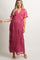 woman wearing a pink embroidered maternity maxi dress, holding her baby bump, with short sleeves and a flowy silhouette