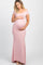 woman wearing a light pink short sleeve maternity dress, standing outdoors and holding her baby bump