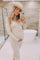 woman wearing a cream ribbed maternity dress and holding her baby bump while posing in a bathroom