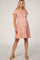 woman wearing a pink floral maternity dress with short sleeves and a ruffled hem, showing off her baby bump
