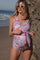 woman wearing a floral print maternity swimsuit with a tied waist and holding her baby bump on the beach