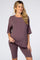 woman wearing a mauve maternity loungewear set with a short sleeve top and bike shorts, showing her baby bump