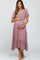 woman wearing a dusty rose maternity dress with short ruffled sleeves and a tiered skirt, holding her baby bump