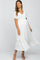 woman wearing a white maternity dress with a v-neck and flutter sleeves, showcasing her baby bump