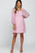 woman wearing a pink maternity dress with textured dots and sheer balloon sleeves, showcasing her baby bump