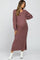 woman wearing a dusty mauve ribbed maternity dress with long sleeves and side slit, showcasing her baby bump