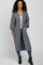 woman wearing a long gray knit cardigan with pockets, styled over a white top and paired with blue jeans