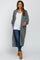 woman wearing a long gray knit maternity cardigan over a white tank top and blue jeans, showing off her baby bump
