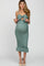 woman wearing a teal maternity dress with a bow detail and ruffled hem, showcasing her baby bump