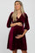 smiling pregnant woman in a burgundy velvet wrap maternity dress with three-quarter sleeves