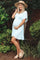 woman wearing a light blue maternity dress with short sleeves and a ruffled hem, showcasing her baby bump