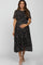 woman wearing a black floral print maternity dress with short sleeves and a flowing skirt, holding her baby bump