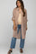 woman wearing a beige maternity shirt dress over a tank top, paired with light blue jeans, showcasing her baby bump