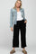 woman wearing a light blue maternity denim jacket over a white tank top and black fringe hem maternity pants