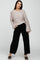 woman wearing a beige oversized sweater and black wide-leg pants with a frayed hem