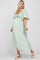woman wearing a light green maternity dress with a tie front and flutter sleeves, showing her baby bump