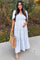 woman wearing a light blue floral maternity maxi dress and holding her baby bump while carrying a tan tote bag