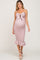 woman wearing a pink maternity dress with a tie front and ruffle hem, showing her baby bump