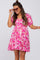 woman wearing a pink floral puff sleeve maternity mini dress and sunglasses