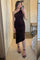 woman wearing a dark brown one-shoulder ruched midi dress and black strappy heels taking a mirror selfie