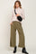 woman wearing cream turtleneck sweater olive green wide leg pants and black leather boots