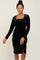 woman wearing a long sleeve black velvet midi dress with a square neckline and side slit