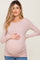 woman wearing a pale pink long sleeve maternity top and holding her baby bump