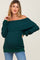 woman wearing a dark green off-the-shoulder maternity sweater and blue jeans