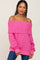 woman wearing a pink off-the-shoulder textured sweater with long sleeves and ribbed cuffs