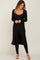 woman wearing a black ribbed long cardigan over a matching black jumpsuit and beige slide sandals