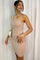 woman wearing a beige ribbed halter neck bodycon dress with a white shoulder bag against white curtains