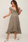 woman wearing a sage green off-shoulder maternity dress with a tie front detail and ruffled hem, showing a baby bump