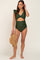 woman wearing a green maternity swimsuit with ruffle sleeves and a cut-out detail, holding a straw hat and showing her baby bump