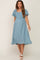 woman wearing a blue maternity dress with flutter sleeves and a smocked waist, showcasing her baby bump