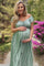 woman wearing a green striped off-the-shoulder maternity dress and holding her baby bump