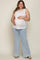 woman wearing a white sleeveless maternity top and light blue flared jeans, cradling her baby bump