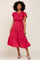Woman wearing a pink floral smocked midi dress with ruffled sleeves and tiered skirt