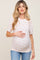 woman wearing a cream floral maternity top with short sleeves and a baby bump visible