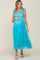 woman wearing a light blue smocked maternity dress with ruffled straps and tiered tulle skirt, holding her baby bump